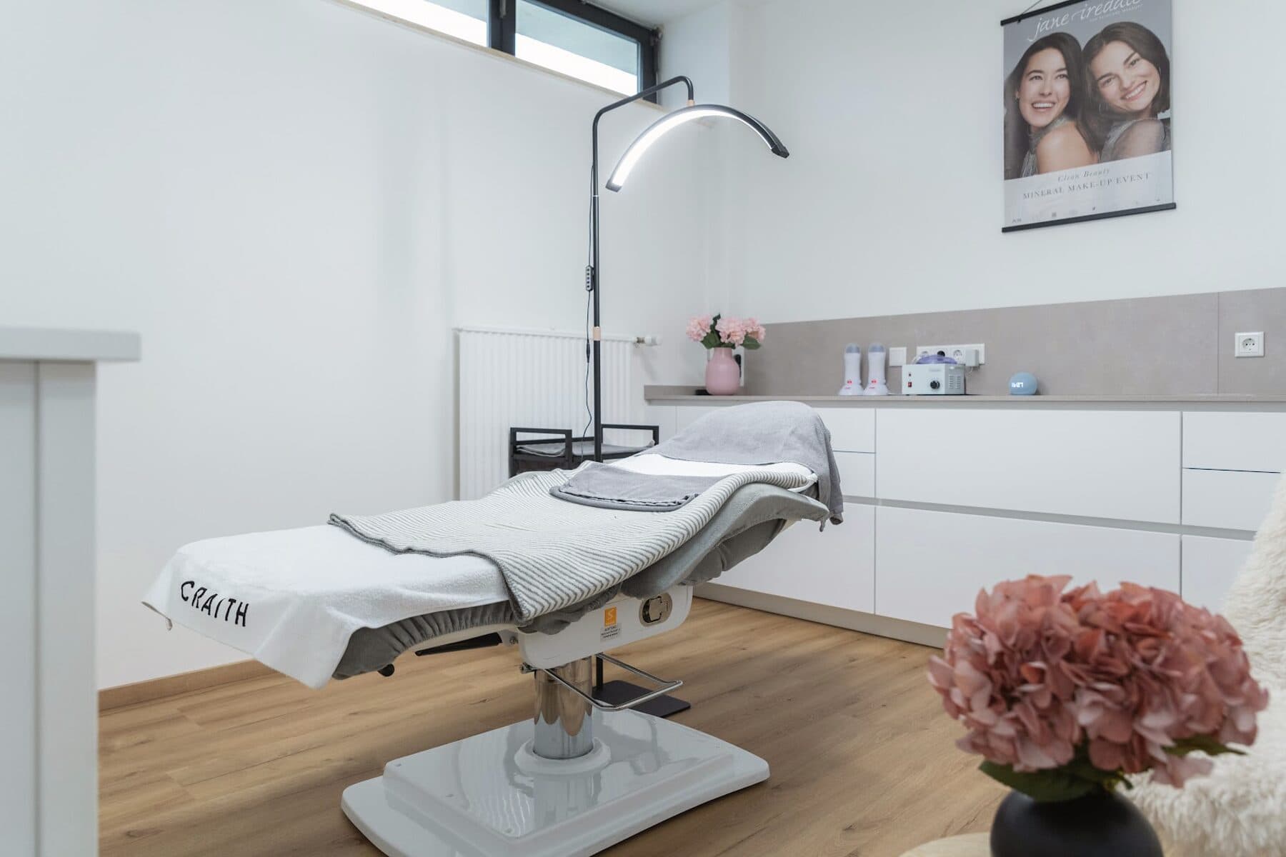 Behandlungsraum im Beautyloft: Liege mit Craith-Tuch, Lupenleuchte und heller Arbeitsfläche mit Hortensien