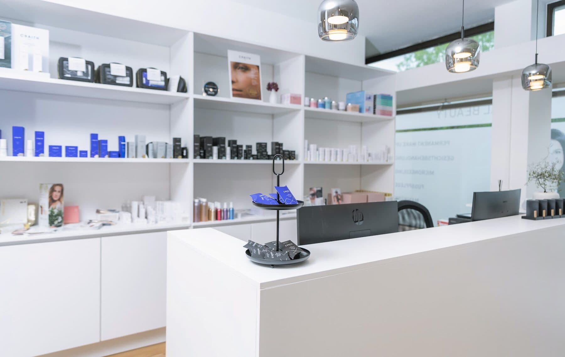 Produktregal im Beautyloft mit Pflegeserien vor dem hellen Empfangstresen