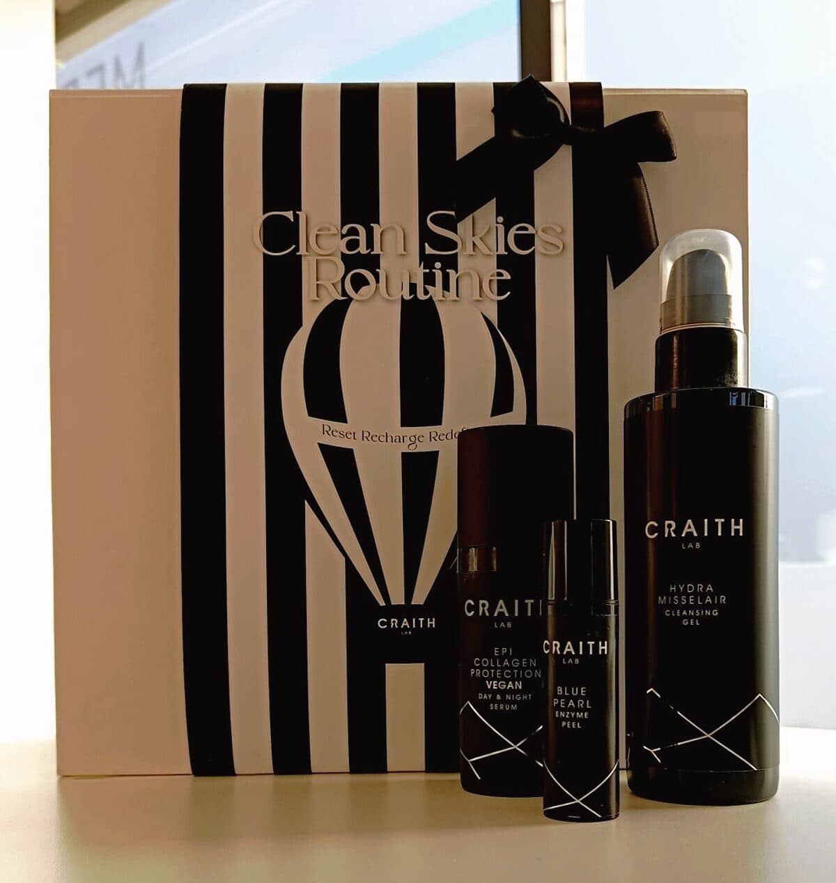 Craith-Lab-Produkte der Clean-Skies-Routine in schwarzen Flaschen vor gestreifter Verpackung